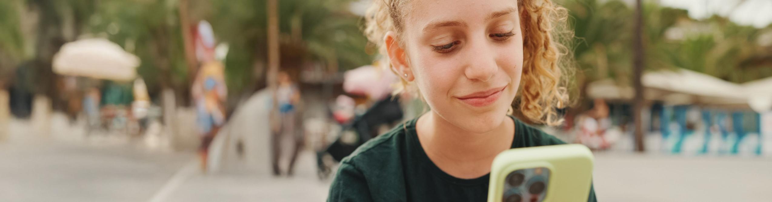 A young person looking at a smartphone outdoors