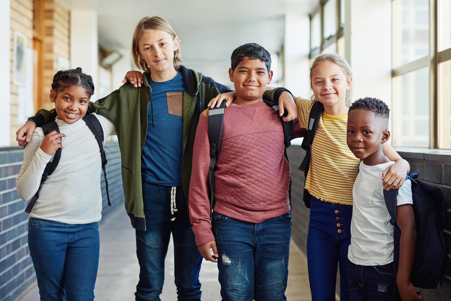 A group of school-age children standing together in a school hallway